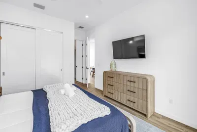Bright modern bedroom with TV, dresser, and serene minimalist style