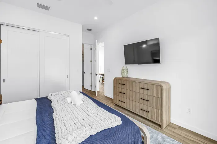 Bright modern bedroom with TV, dresser, and serene minimalist style