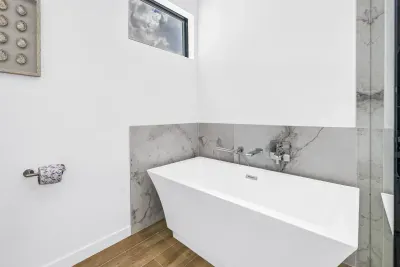Bright modern bathroom with freestanding soaking tub and marble accents