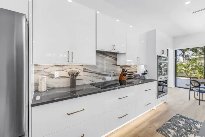 Bright designer kitchen with sleek finishes and sunny dining access