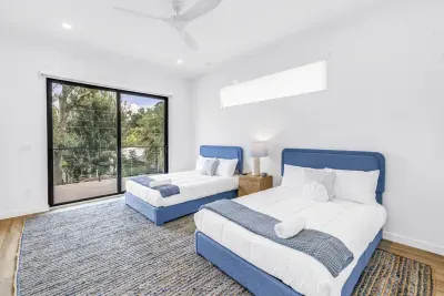 Bright double bedroom with two plush beds and peaceful treetop views
