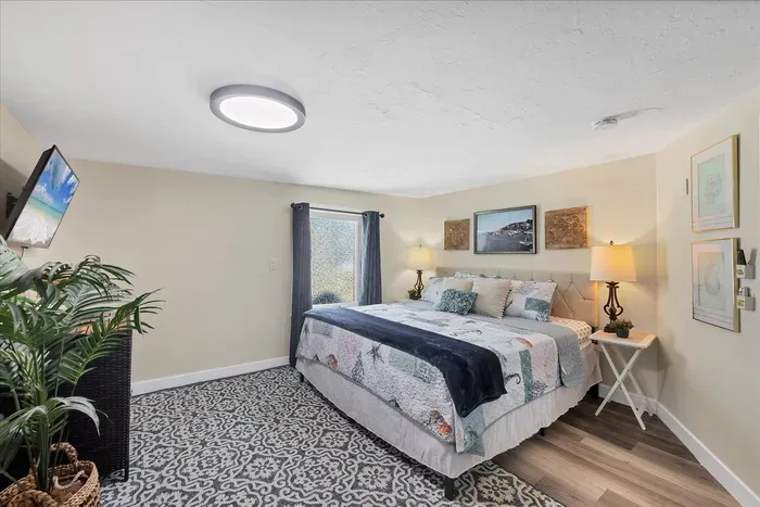Serene king bedroom with coastal decor, TV, and soft lighting.