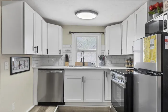 Bright U-shaped kitchen with stainless appliances and subway tile