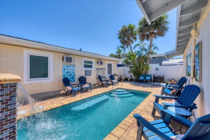 Private pool oasis with waterfall, Adirondack seating and palms.