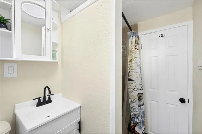 Bright, compact bath with storage, black fixtures & walk-in shower