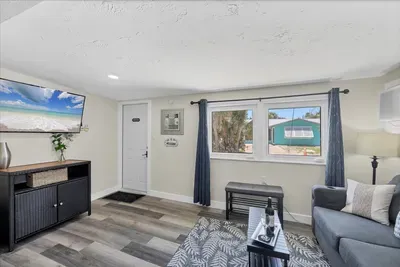 Sunny coastal lounge with smart TV, AC, and comfy sofa seating.
