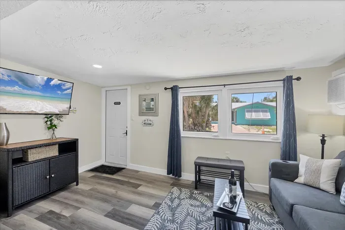 Sunny coastal lounge with smart TV, AC, and comfy sofa seating.