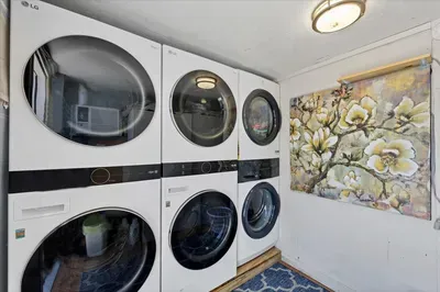 Laundry room with 3 LG washer/dryer sets, artful decor & rug