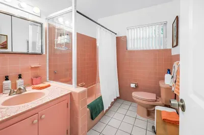 Charming retro pink bathroom with bright light and tub-shower combo