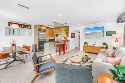 Bright open-plan living with stylish decor, breakfast bar, and big TV