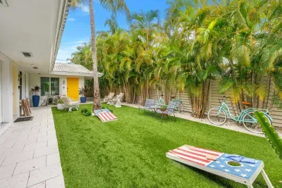 Tropical private courtyard with lawn games, patio seating, and lush palms