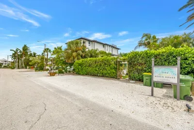 Tropical Lido Beach House entrance on a quiet, palm-lined coastal street