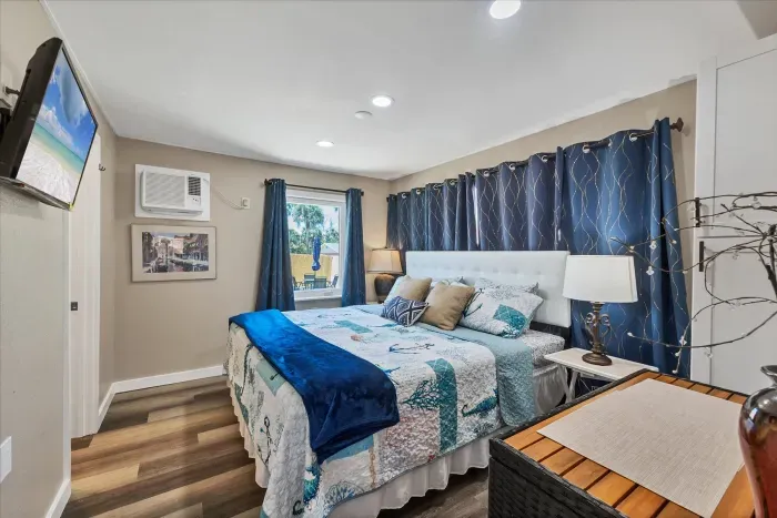 Cozy beach-themed bedroom with AC, blackout drapes, TV & warm lighting
