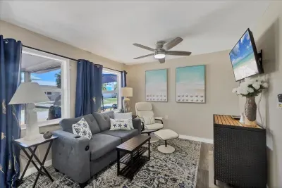 Sunny coastal living room with smart TV, plush seating, and patio views