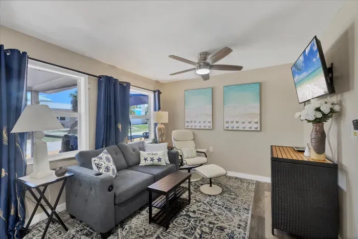 Sunny coastal living room with smart TV, plush seating, and patio views