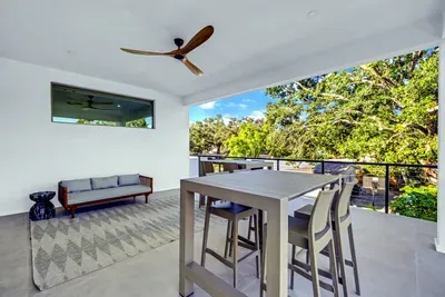 Covered balcony with dining table, lounge seating, and tranquil tree views