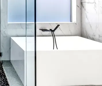 Spa-like bathroom with soaking tub, marble walls, and sleek black fixtures