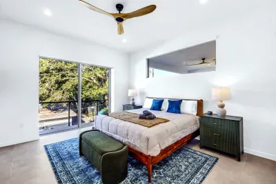 Bright king bedroom with leafy views, ceiling fan, and stylish modern decor