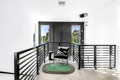 Bright modern landing with cozy seating, tall windows, and stylish design