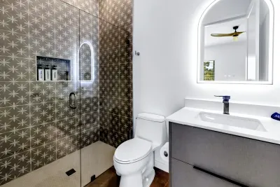 Modern designer bathroom with glass walk-in shower and illuminated mirror