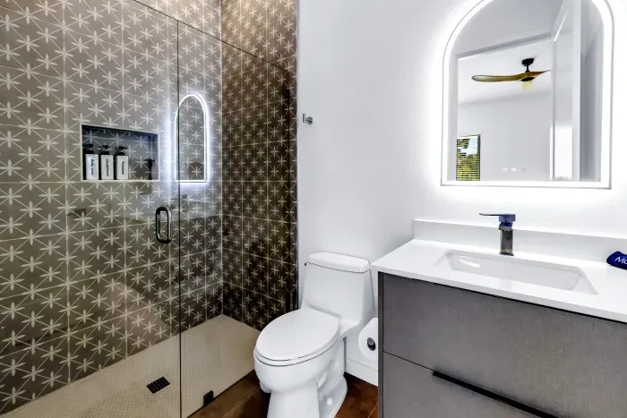 Modern designer bathroom with glass walk-in shower and illuminated mirror