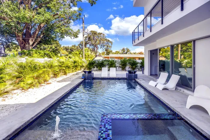 Modern private pool with sun shelf, loungers, and lush tropical surrounds