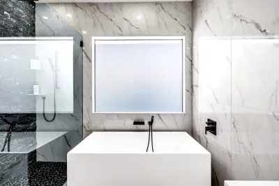 Spa-like marble bathroom with soaking tub, backlit mirror, and luxe shower