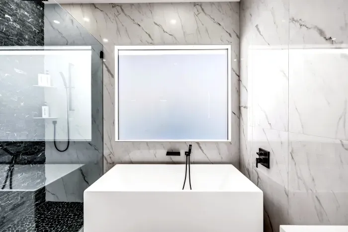 Spa-like marble bathroom with soaking tub, backlit mirror, and luxe shower