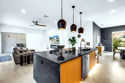 Bright open-concept kitchen with sleek island, stylish lighting, and airy living space