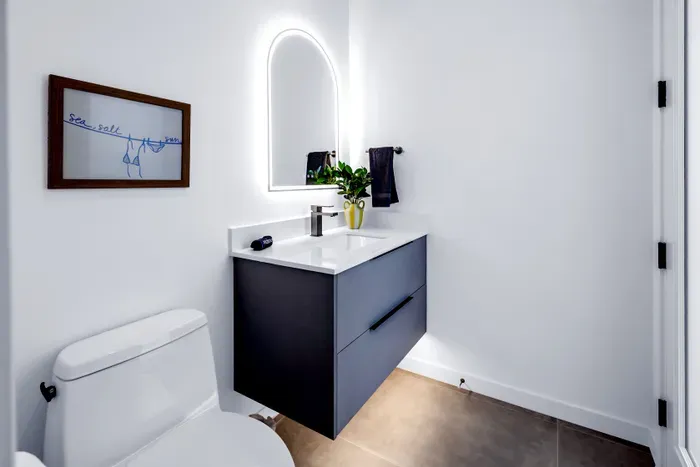 Bright modern bathroom with floating vanity and elegant backlit mirror