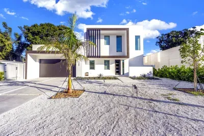 Modern two-story home with sleek design, wide driveway, and tropical curb appeal