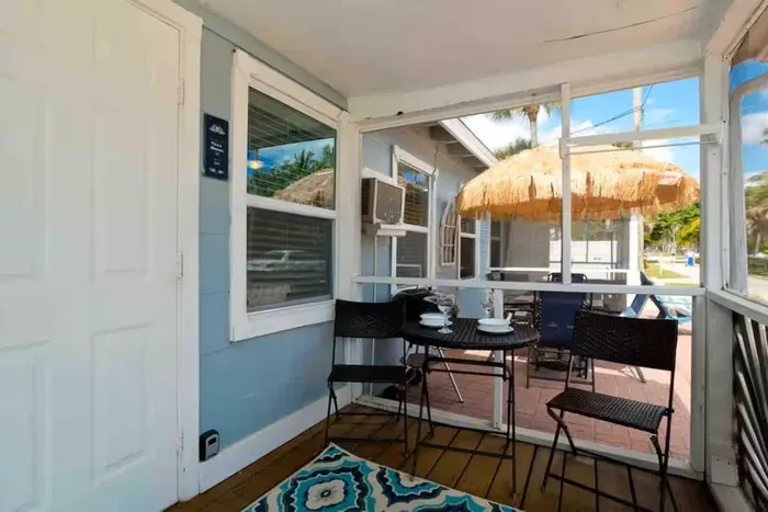 Screened porch + sunny patio with tiki umbrella—your coastal chill spot.
