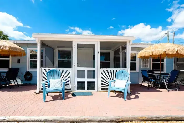 Coastal cottage with screened porch, patio seating & tiki umbrellas