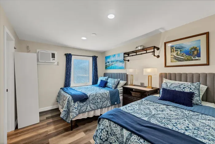 Coastal-chic room with two comfy beds, AC, wood floors, and soft lighting.