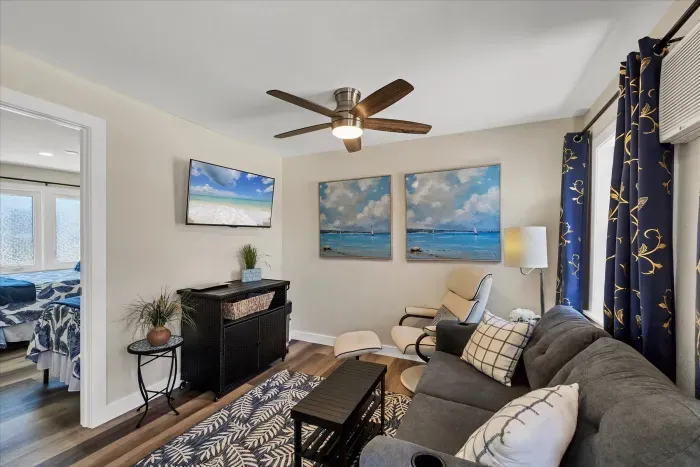 Coastal-chic living room with TV, recliner, ceiling fan and AC—bright, comfy stay