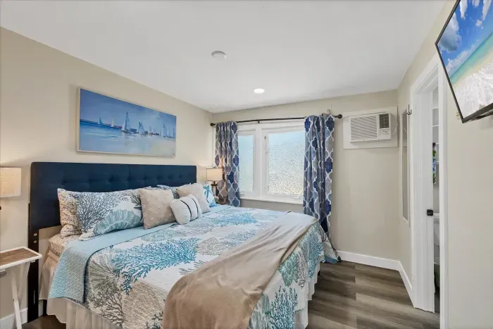 Coastal king bedroom with TV, AC, ensuite, and sunny windows