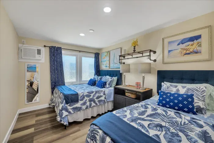 Sunny coastal room with two beds, AC, and large frosted windows