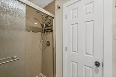 Sleek tiled walk-in shower with glass door and pebble floor