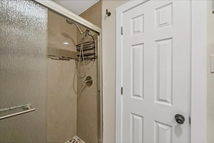 Sleek tiled walk-in shower with glass door and pebble floor