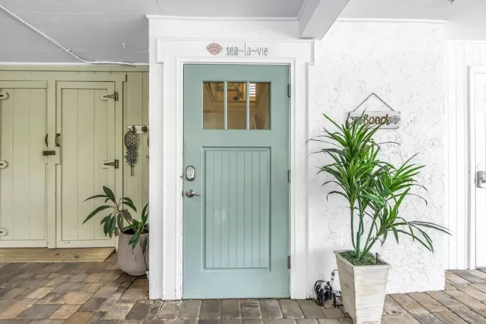 Entryway Delight: Bright mint door welcomes you to your beach getaway, surrounded by tropical vibes!