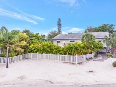Large parking area: Embrace island vibes with lush landscaping and serene white fencing!