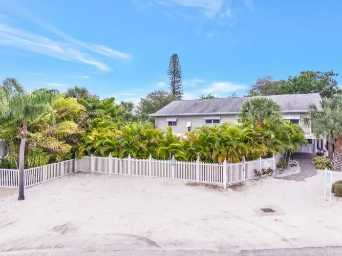 Large parking area: Embrace island vibes with lush landscaping and serene white fencing!