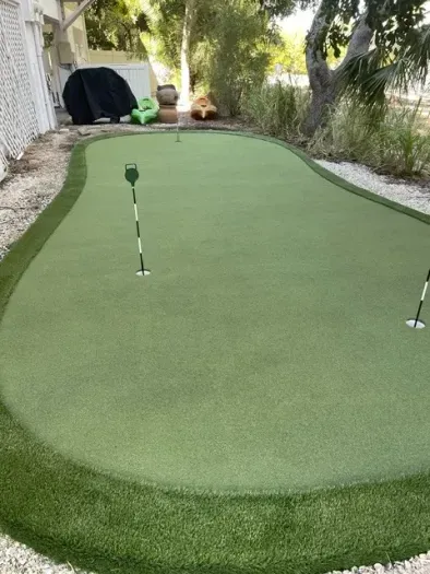 Private backyard putting green with flags—lush, shaded practice spot.