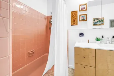 Charming retro bath with pink tile, bright vanity, and stylish vintage touches