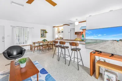 Bright coastal living space with breakfast bar, dining area, and TV