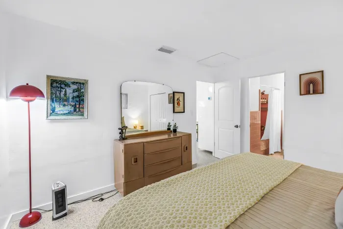 Bright, cozy bedroom with stylish dresser and easy bathroom access