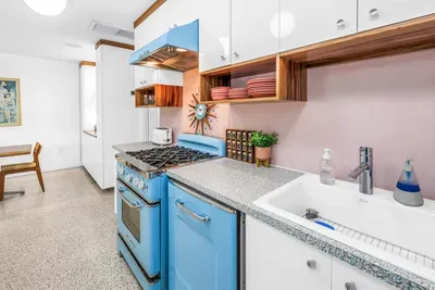 Charming retro kitchen with blue gas range, farmhouse sink, and open shelving