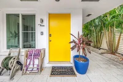 Bright tropical entry with bold yellow door and lush side garden path