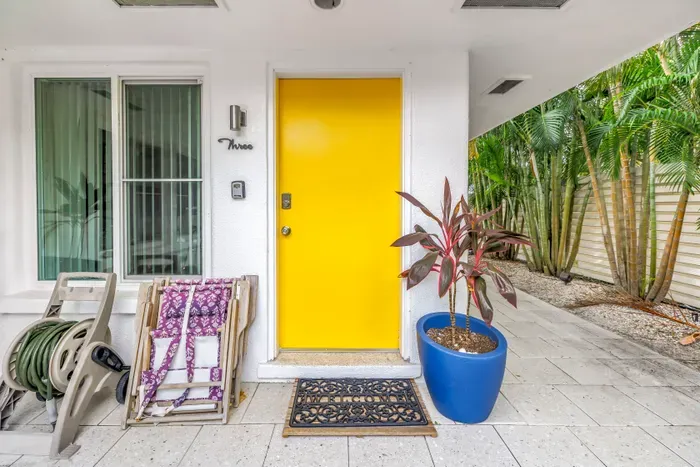 Bright tropical entry with bold yellow door and lush side garden path