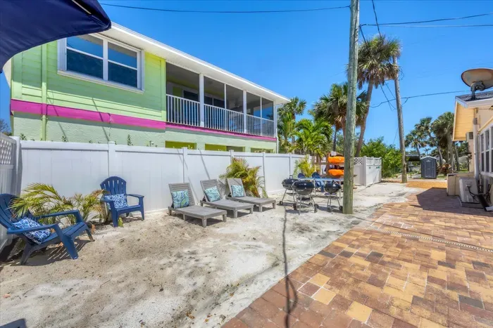 Sunny beachy courtyard with loungers, dining area, and screened balcony